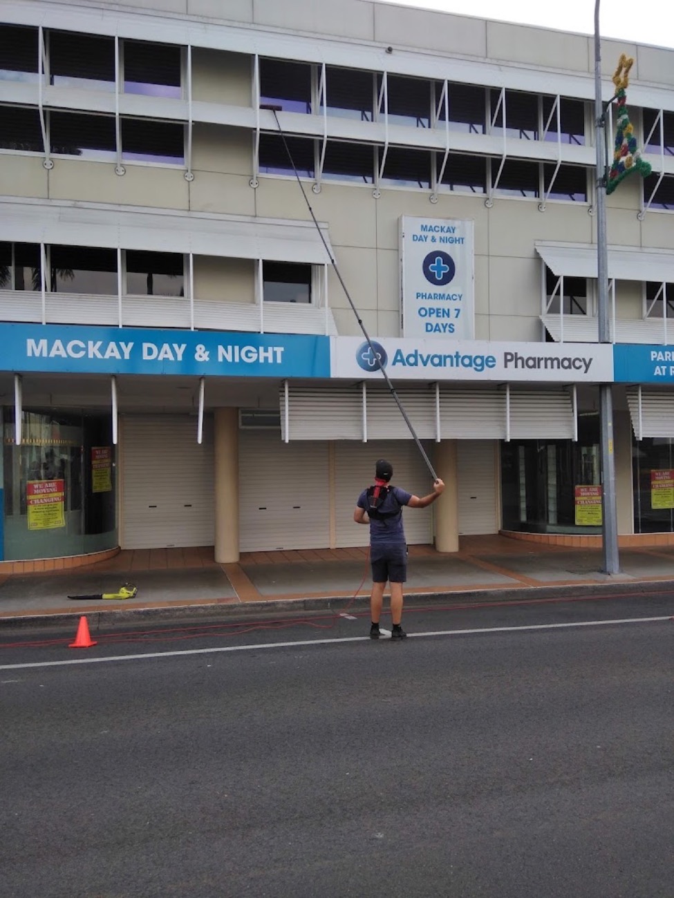 A man using a water-fed pole on a multi-storey building on a Mackay street