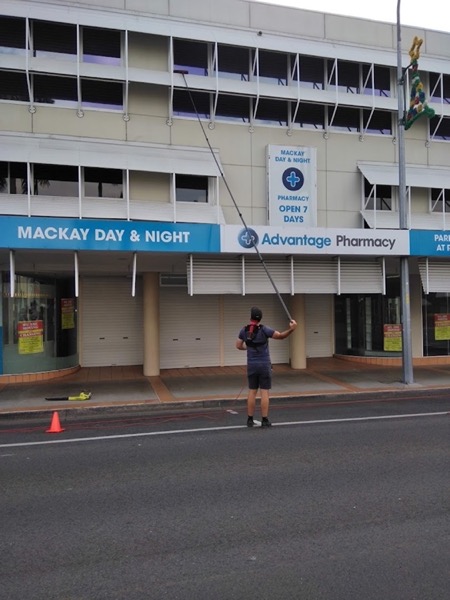 A man using a water-fed pole on a multi-storey building on a Mackay street