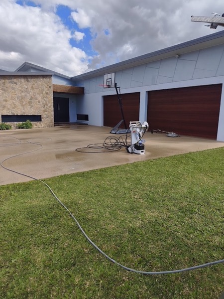 A driveway with a hose running up to a garage door