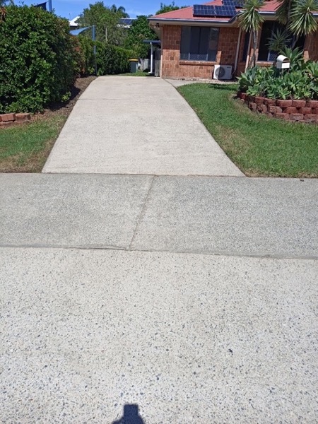 A concrete footpath beside a lawn and garden bed