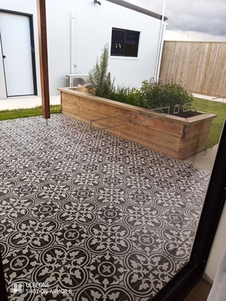 A pebbled garden bed beside a rendered planter